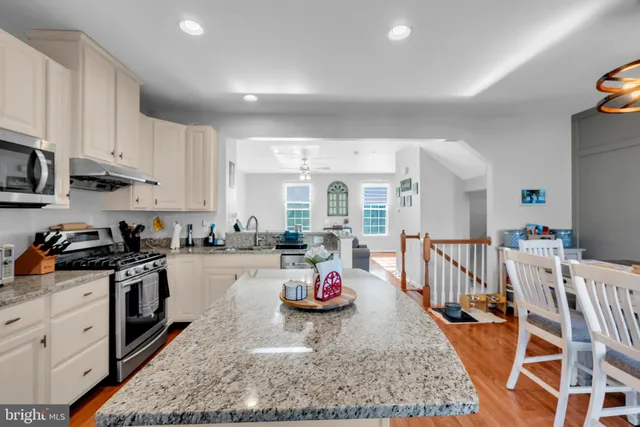 a kitchen with stainless steel appliances granite countertop a stove top oven a sink a dining table and chairs