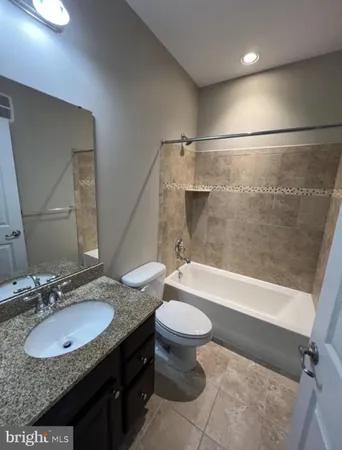 a bathroom with a granite countertop sink toilet mirror and bathtub