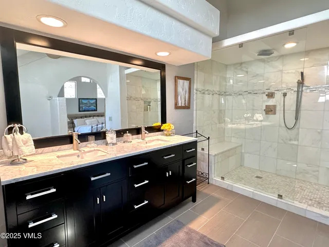 a bathroom with a double vanity sink mirror and shower