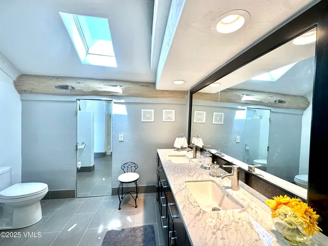 a spacious bathroom with a granite countertop toilet a mirror and a shower