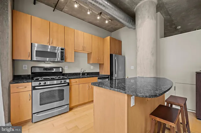 a kitchen with stainless steel appliances granite countertop a stove a sink and a microwave