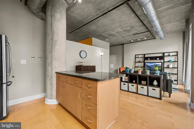 a living room with stainless steel appliances kitchen island granite countertop furniture and a flat screen tv