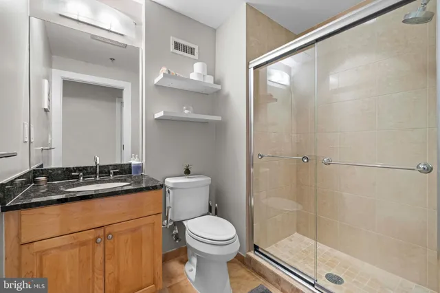 a bathroom with a granite countertop sink toilet and shower