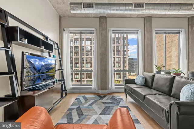 a living room with furniture a flat screen tv and a floor to ceiling window