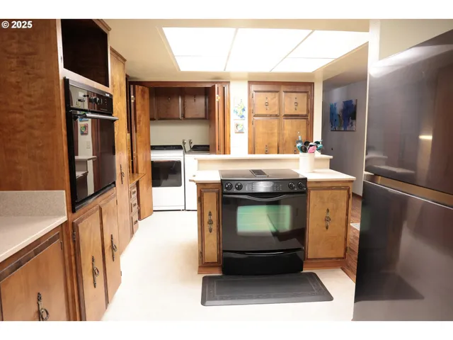 a living room with stainless steel appliances furniture a fireplace and a kitchen view