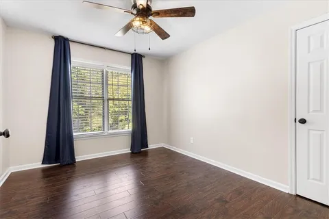 an empty room with wooden floor fan and windows