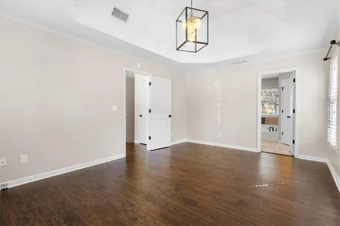 an empty room with wooden floor and hallway