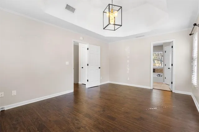 an empty room with wooden floor and hallway