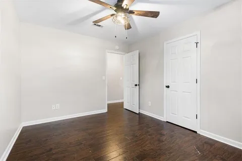 an empty room with wooden floor and ceiling fan