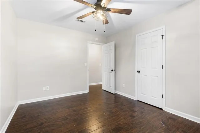 an empty room with wooden floor and ceiling fan