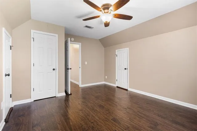 an empty room with wooden floor chandelier fan and closet area