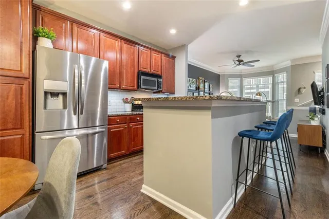a kitchen with stainless steel appliances granite countertop a refrigerator a stove a sink dishwasher a dining table and chairs with wooden floor