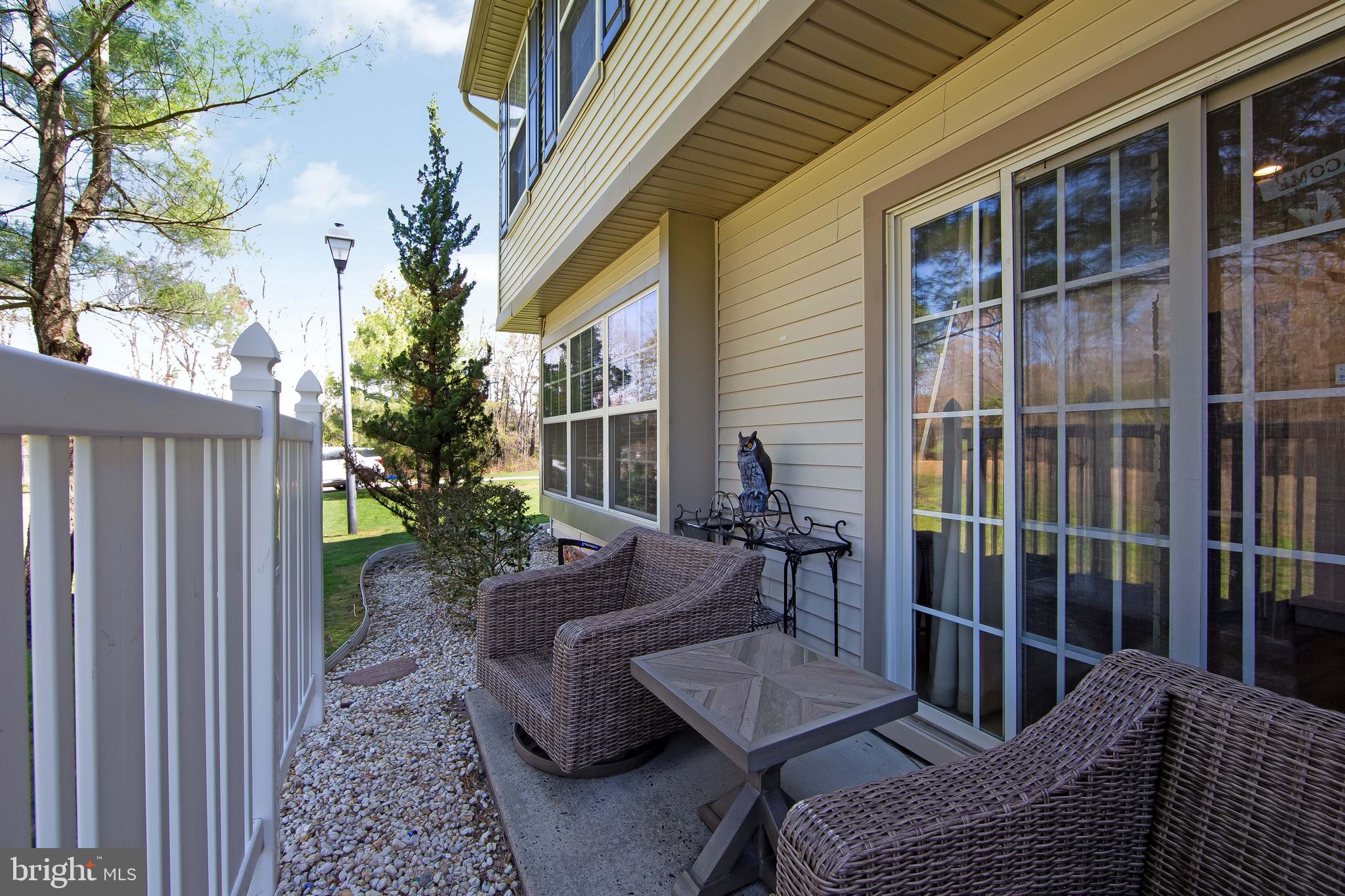 803 Tanglewood Drive Sicklerville, NJ 08081 - Photo 30 of 34 a view of a patio with couches chairs potted plants and floor to ceiling window and wooden fence