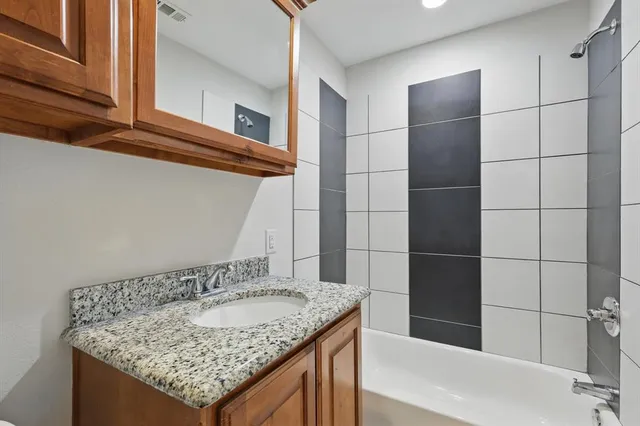 a bathroom with a granite countertop sink and a shower
