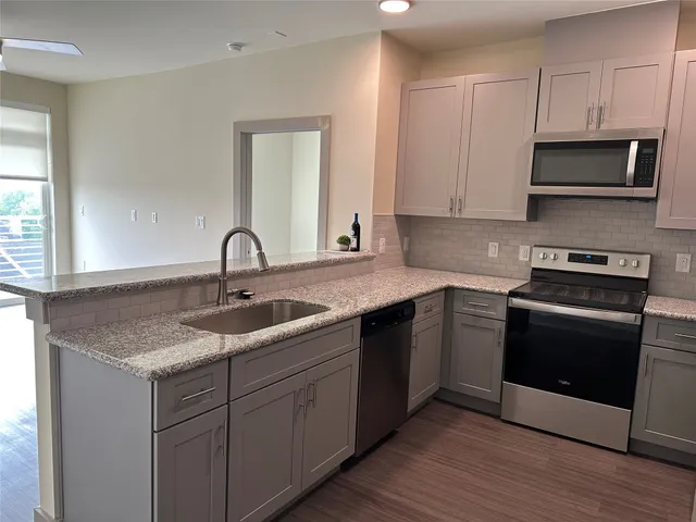 a kitchen with stainless steel appliances granite countertop a sink and a microwave