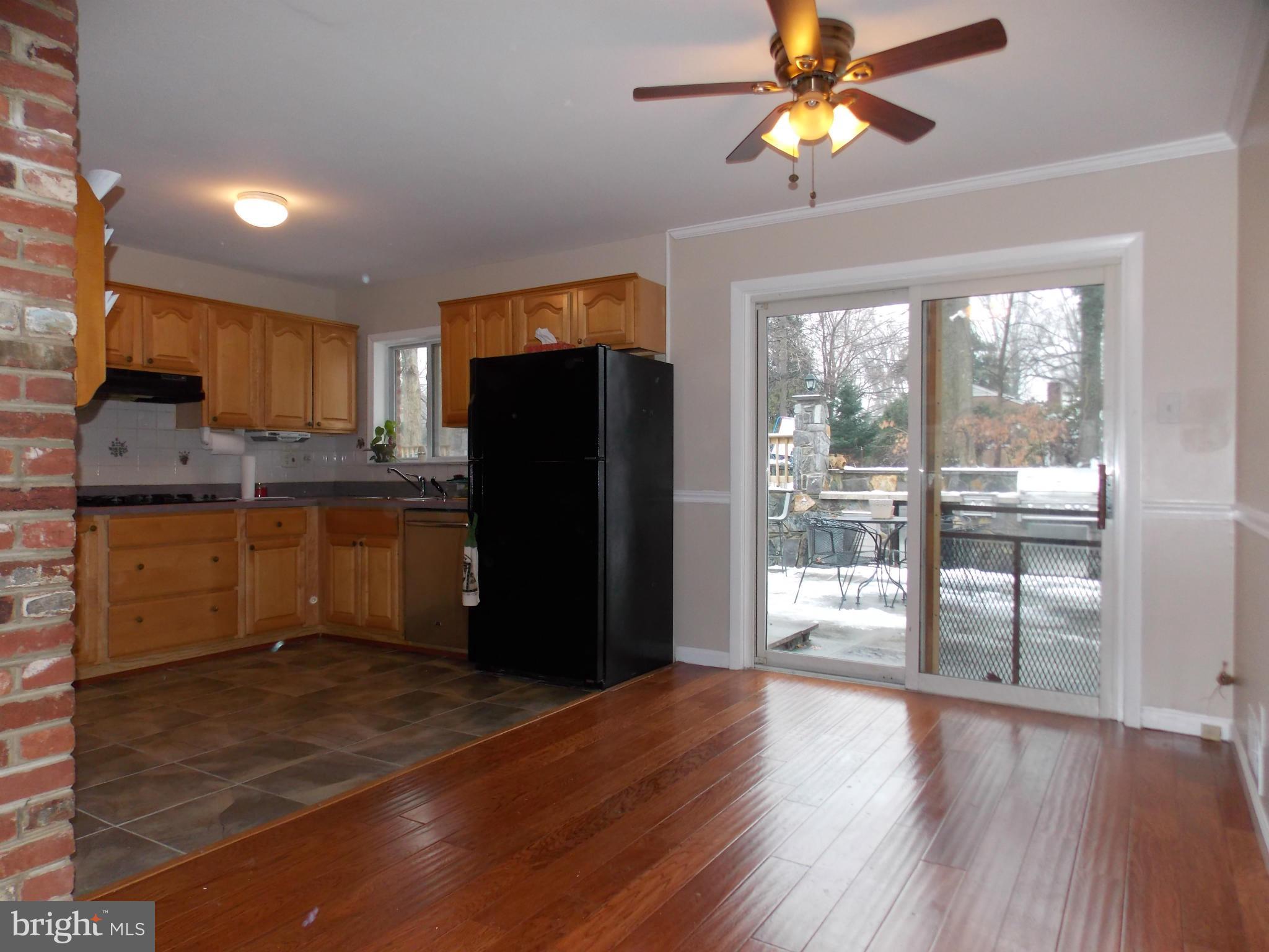 7125 Catlett Street Springfield, VA 22151 - Photo 10 of 26 a kitchen with stainless steel appliances granite countertop a refrigerator a stove a microwave oven with a dining table and wooden floor