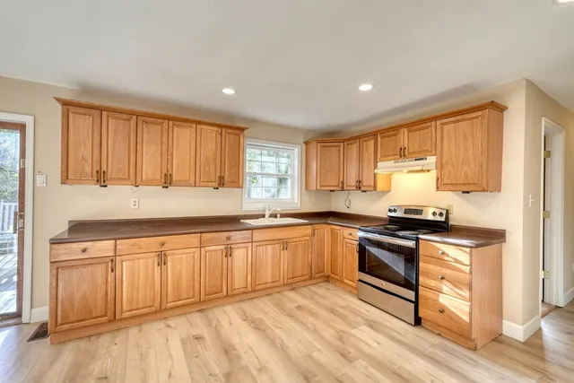 a kitchen with granite countertop a sink stainless steel appliances and window