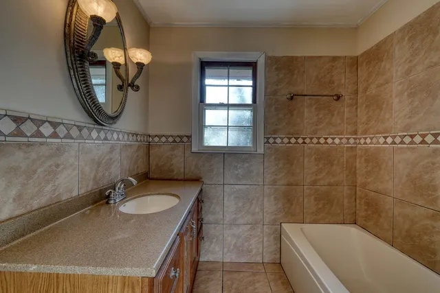 a bathroom with a granite countertop sink a mirror and bathtub