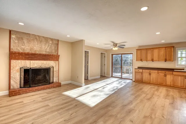 a view of an empty room with wooden floor fireplace and a window
