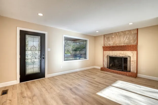 a view of an empty room with window and fire place