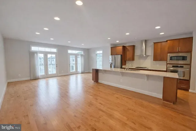 a large kitchen with stainless steel appliances a large counter top a refrigerator a sink and a stove