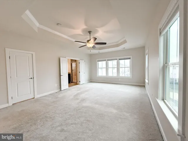 an empty room with chandelier fan and windows