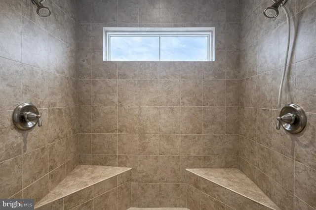 an empty room with chandelier fan and windows