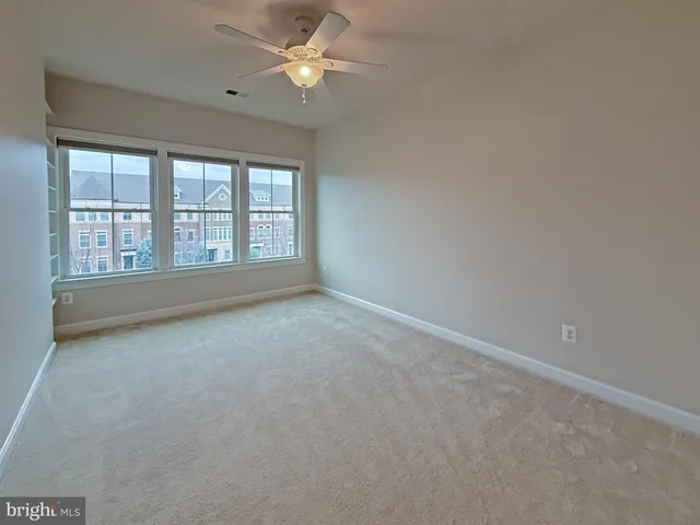 a view of an empty room with a ceiling fan and window