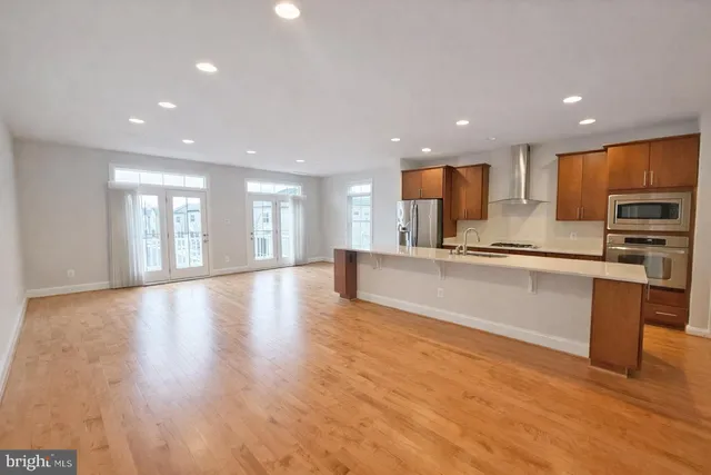 a view of kitchen with kitchen island granite countertop stainless steel appliances refrigerator and cabinets