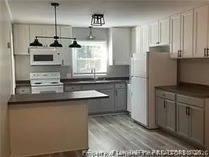 a kitchen with kitchen island white cabinets and refrigerator