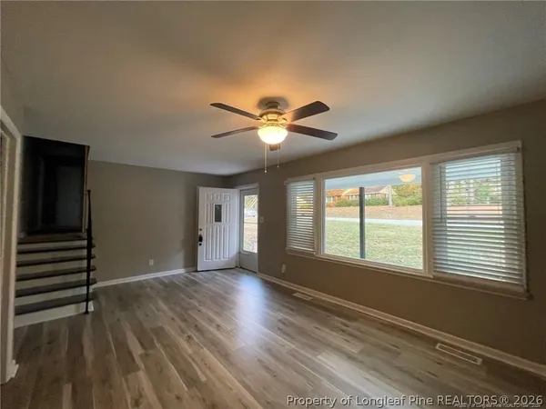 a view of an empty room with wooden floor and a window