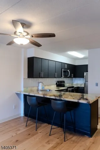 a kitchen with stainless steel appliances kitchen island granite countertop a table chairs in it and wooden floors