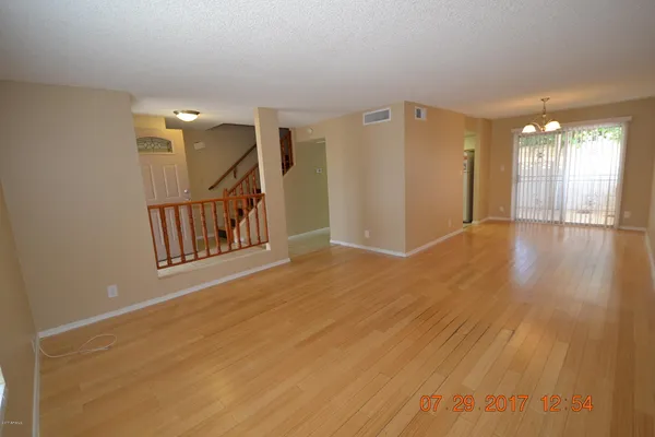 a view of an empty room with wooden floor and windows