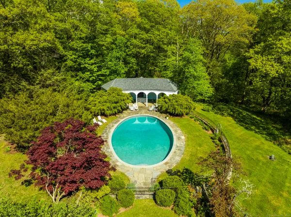 an aerial view of a house with swimming pool and trees