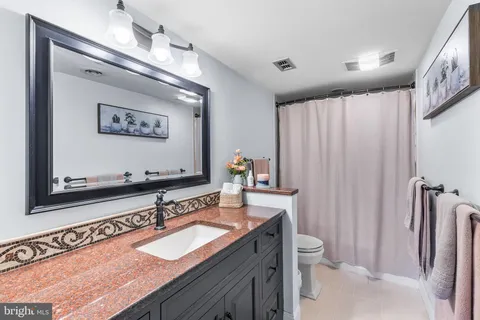 a bathroom with a granite countertop sink a toilet and a mirror