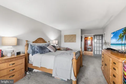 a bedroom with a bed and a flat tv screen on dresser