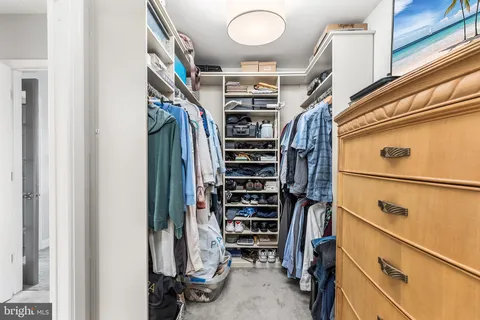 a view of walk in closet with clothes and shoes