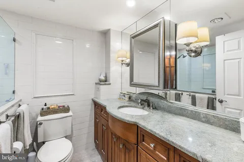 a bathroom with a granite countertop sink toilet and mirror