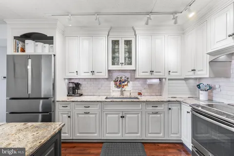 a kitchen with kitchen island granite countertop a sink stainless steel appliances and cabinets