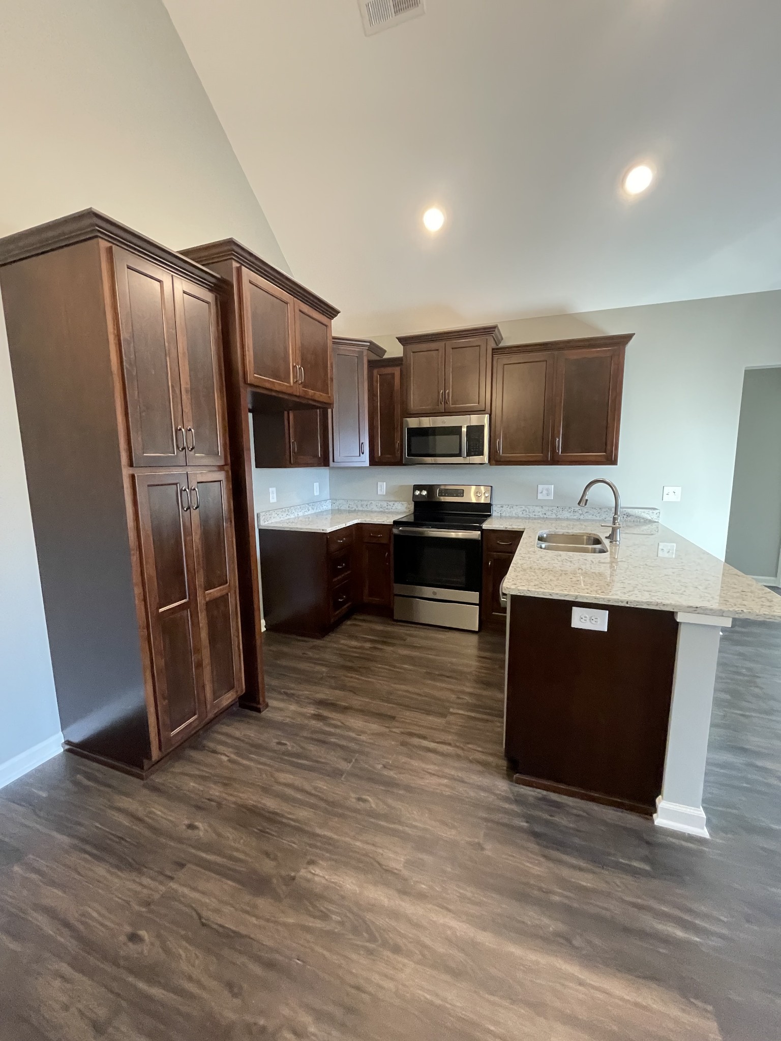 128 Eno Road Dickson, TN 37055 - Photo 7 of 12 a large kitchen with stainless steel appliances a refrigerator a sink dishwasher a stove and white cabinets with wooden floor