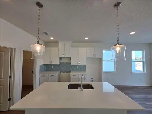 a kitchen with stainless steel appliances kitchen island granite countertop a sink a refrigerator and a granite counter tops