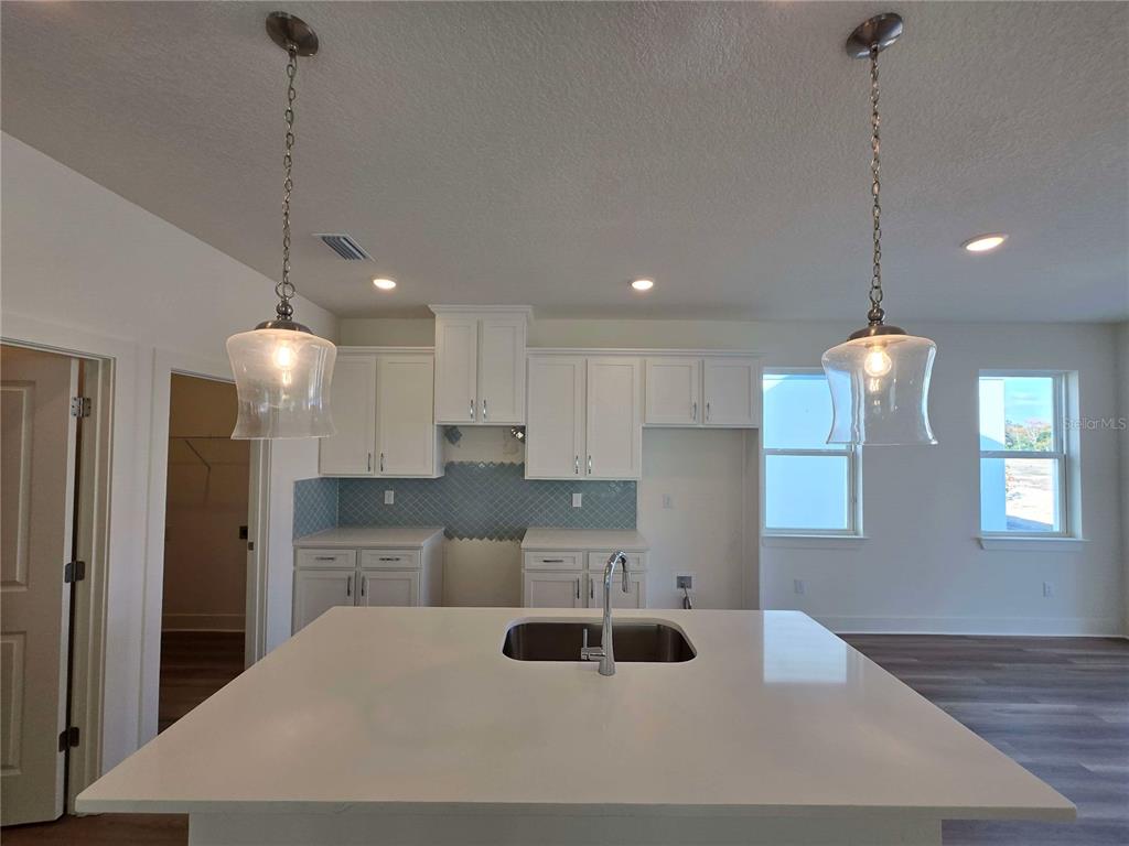 3827 Daybreak Run Loop Spring Hill, FL 34609 - Photo 4 of 14 a kitchen with stainless steel appliances kitchen island granite countertop a sink a refrigerator and a granite counter tops