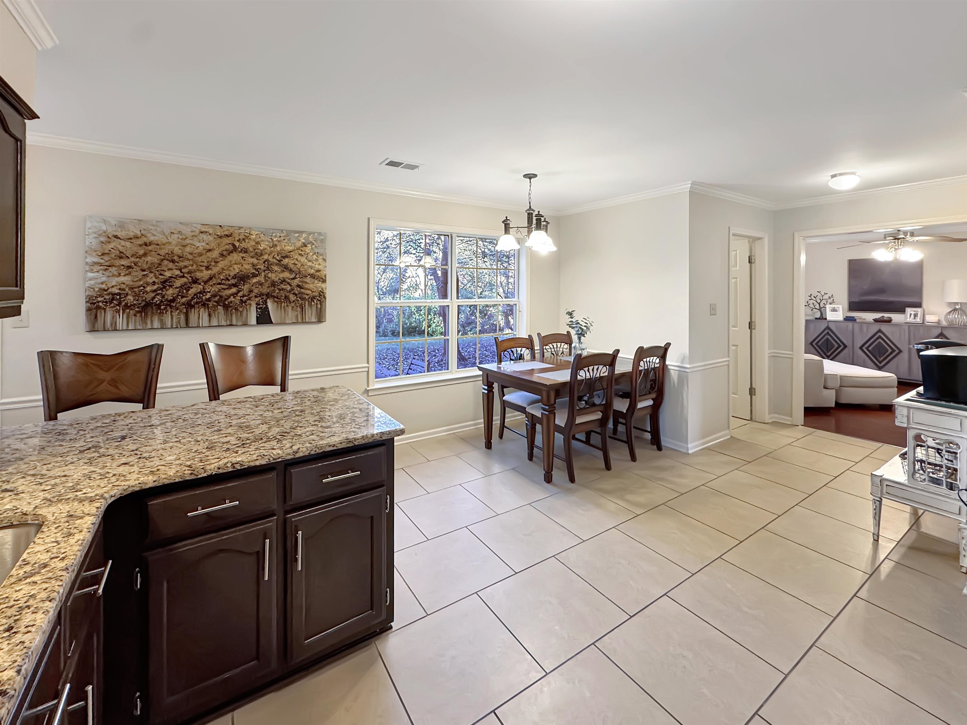 340 Scarlett's Way Collierville, TN 38017 - Photo 11 of 40 Kitchen featuring dark brown cabinets, light stone counters, decorative light fixtures, crown molding, and light tile patterned floors