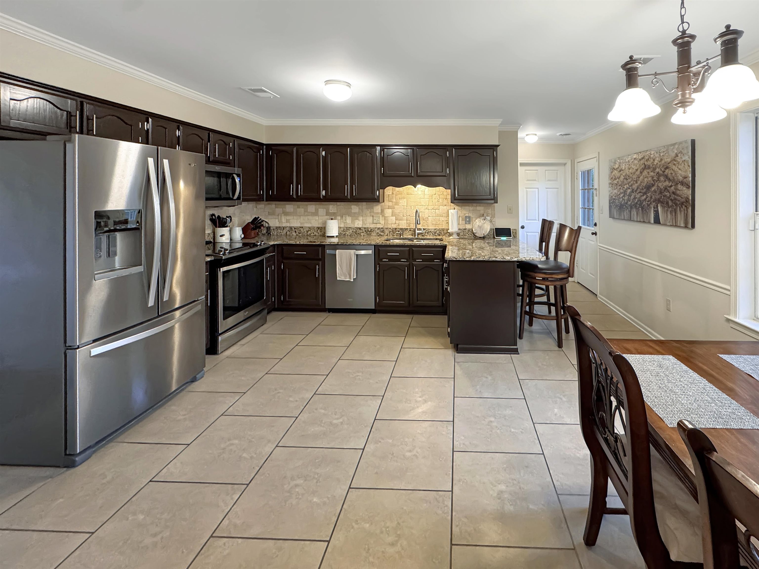 340 Scarlett's Way Collierville, TN 38017 - Photo 12 of 40 Kitchen with stainless steel appliances, ornamental molding, backsplash, a breakfast bar area, and a chandelier
