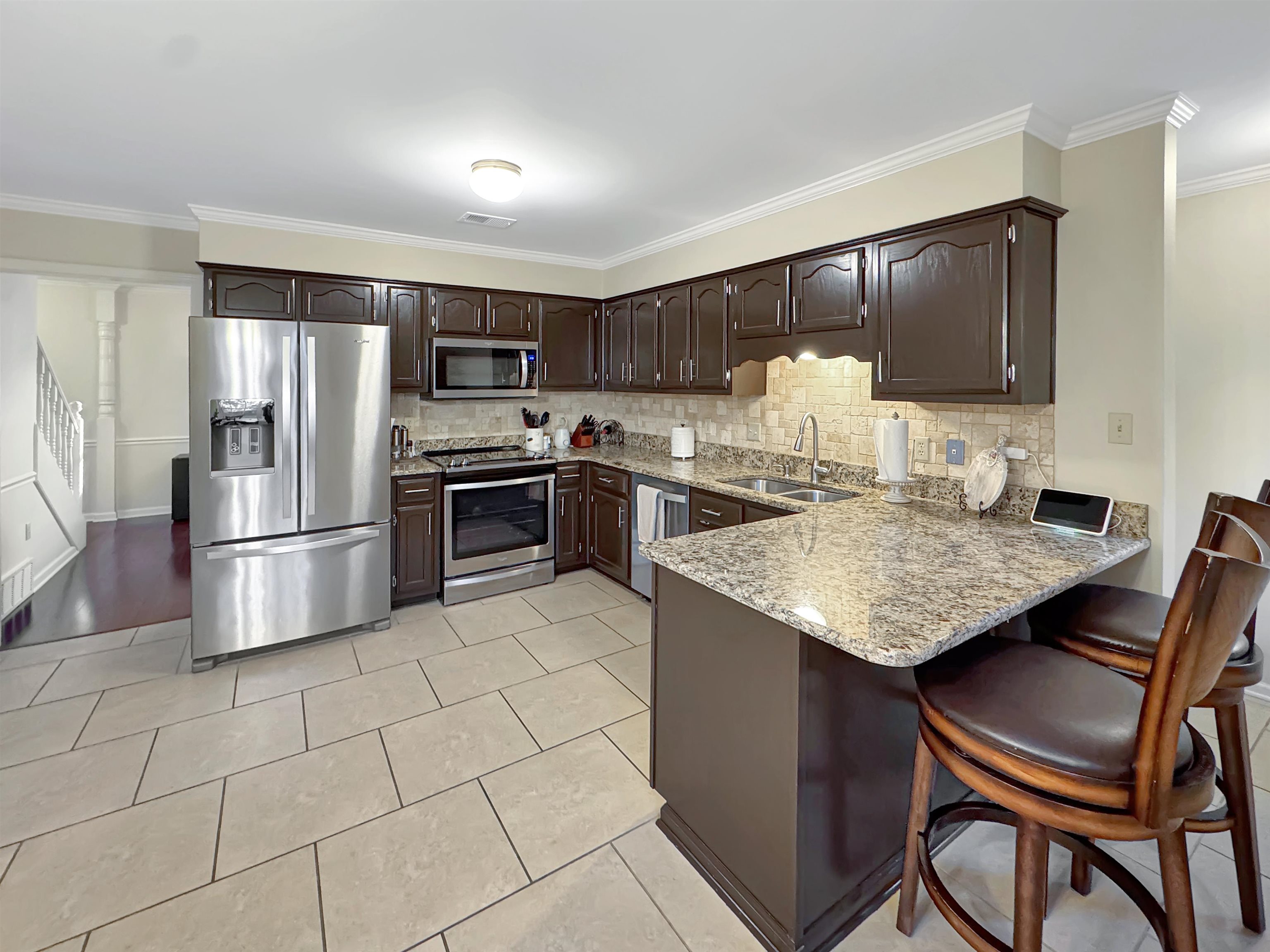 340 Scarlett's Way Collierville, TN 38017 - Photo 13 of 40 Kitchen featuring ornamental molding, stainless steel appliances, dark brown cabinets, a kitchen breakfast bar, and a peninsula