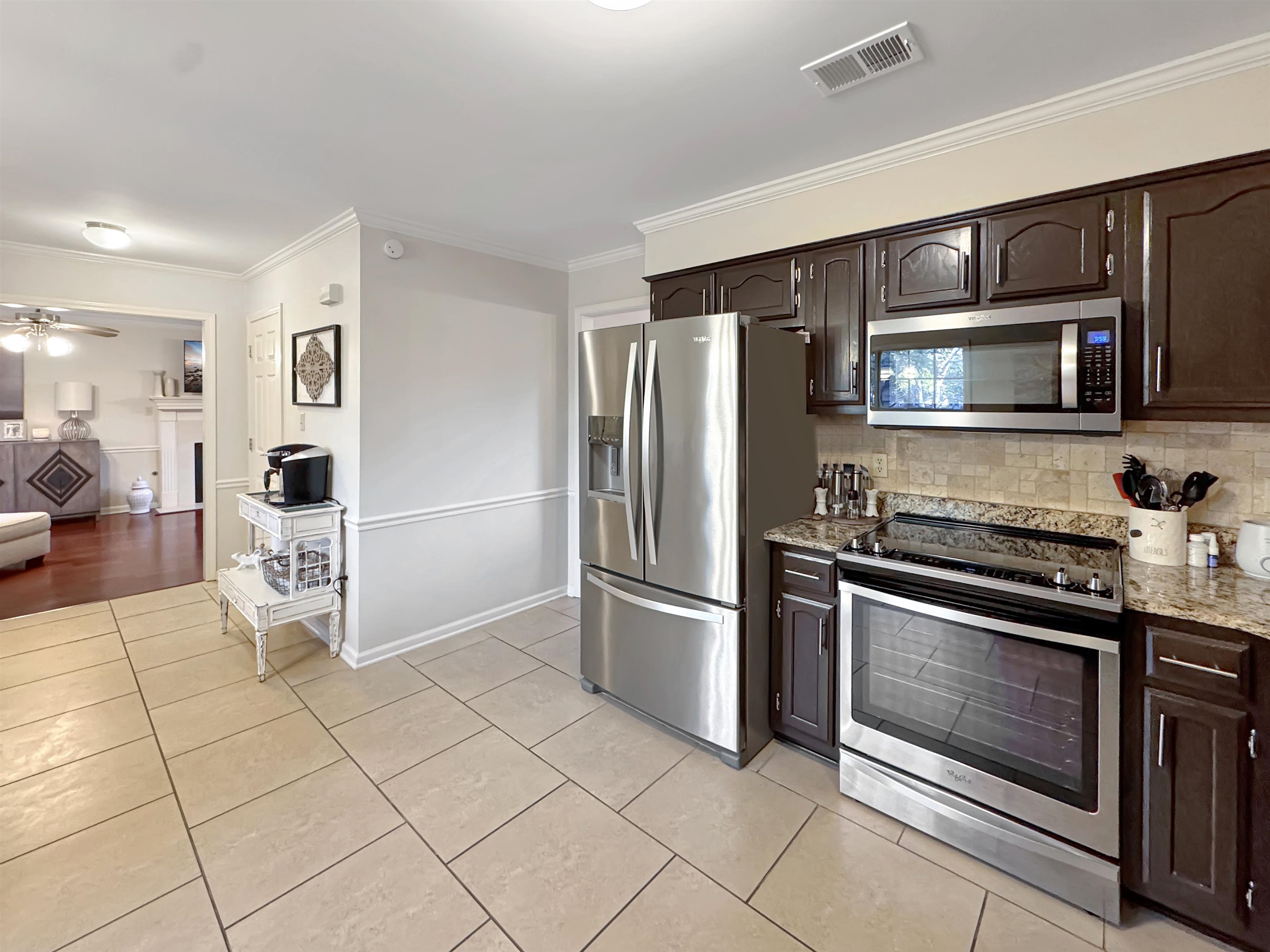 340 Scarlett's Way Collierville, TN 38017 - Photo 15 of 40 Kitchen with appliances with stainless steel finishes, crown molding, dark brown cabinetry, light tile patterned floors, and backsplash