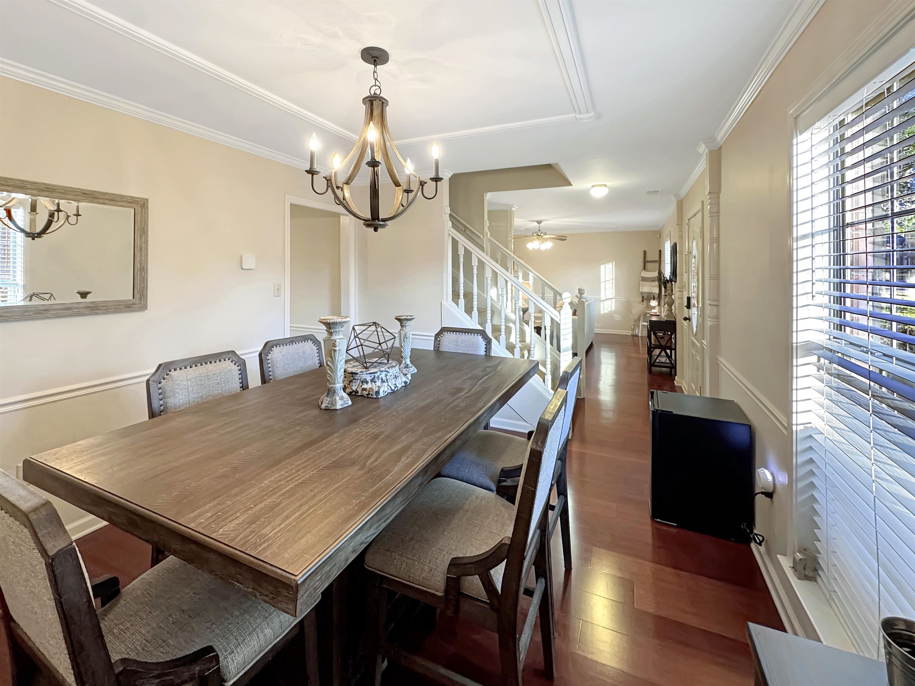 340 Scarlett's Way Collierville, TN 38017 - Photo 19 of 40 Dining room with dark wood-style floors, a ceiling fan, a chandelier, crown molding, and stairs