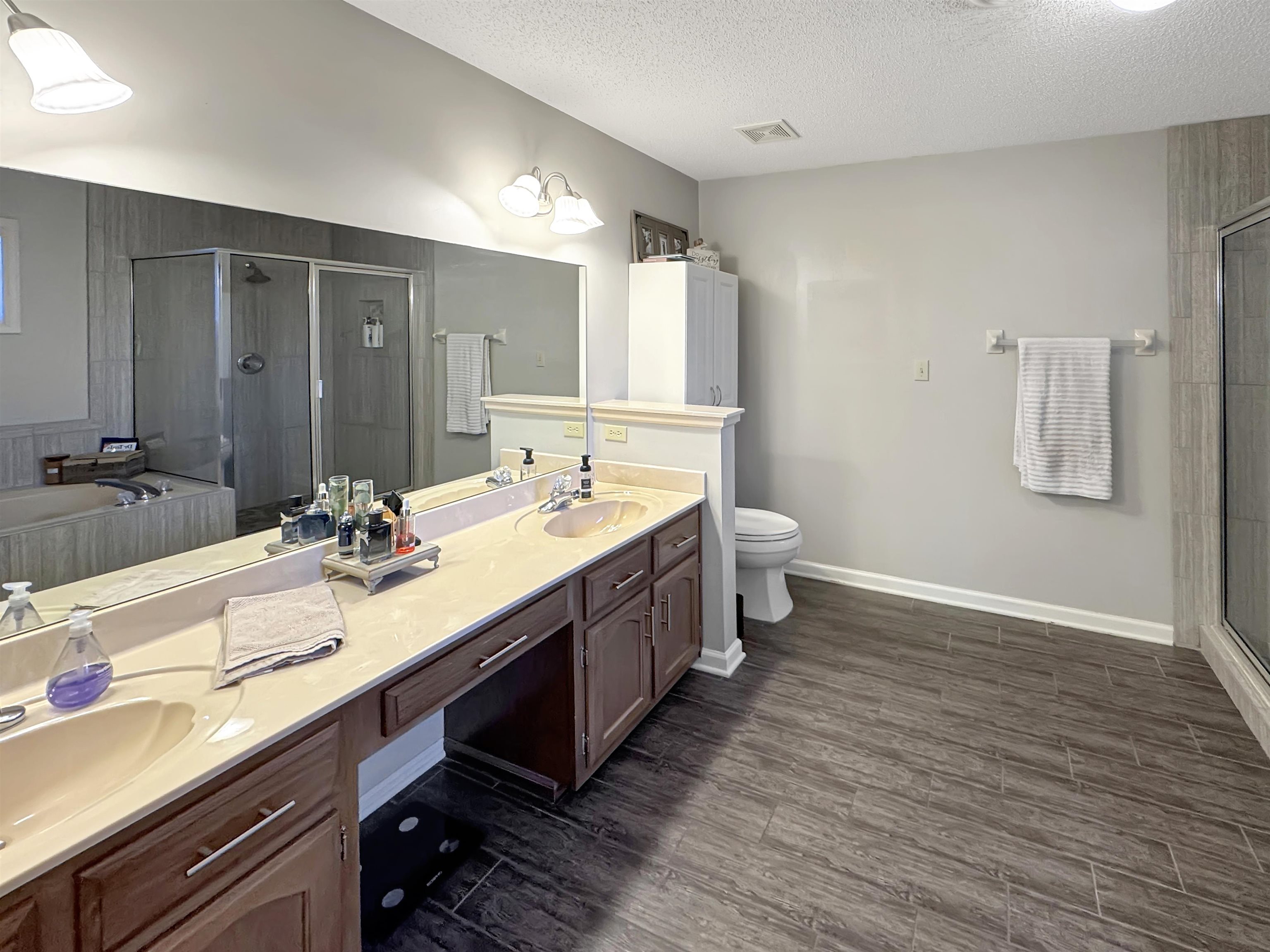 340 Scarlett's Way Collierville, TN 38017 - Photo 24 of 40 Bathroom featuring a bath, a shower stall, dark wood-style flooring, double vanity, and a textured ceiling