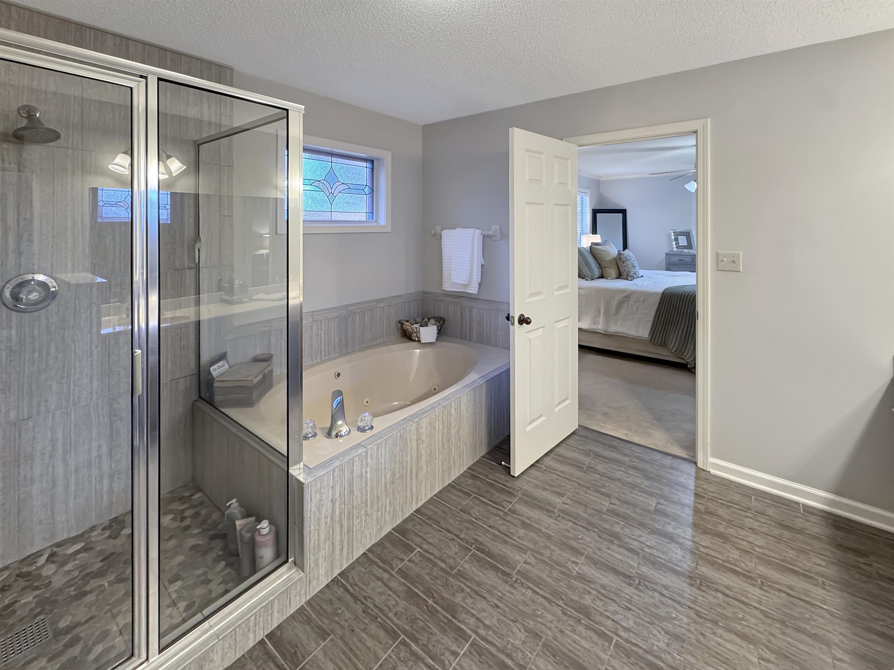 340 Scarlett's Way Collierville, TN 38017 - Photo 26 of 40 Bathroom featuring ensuite bathroom, a shower stall, a tub with jets, wood tiled floors, and a textured ceiling