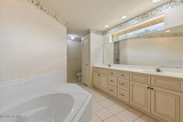 a spacious bathroom with a double vanity sink a mirror and a bathtub